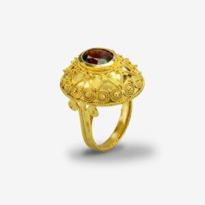 Ornate gold ring with red gemstone.